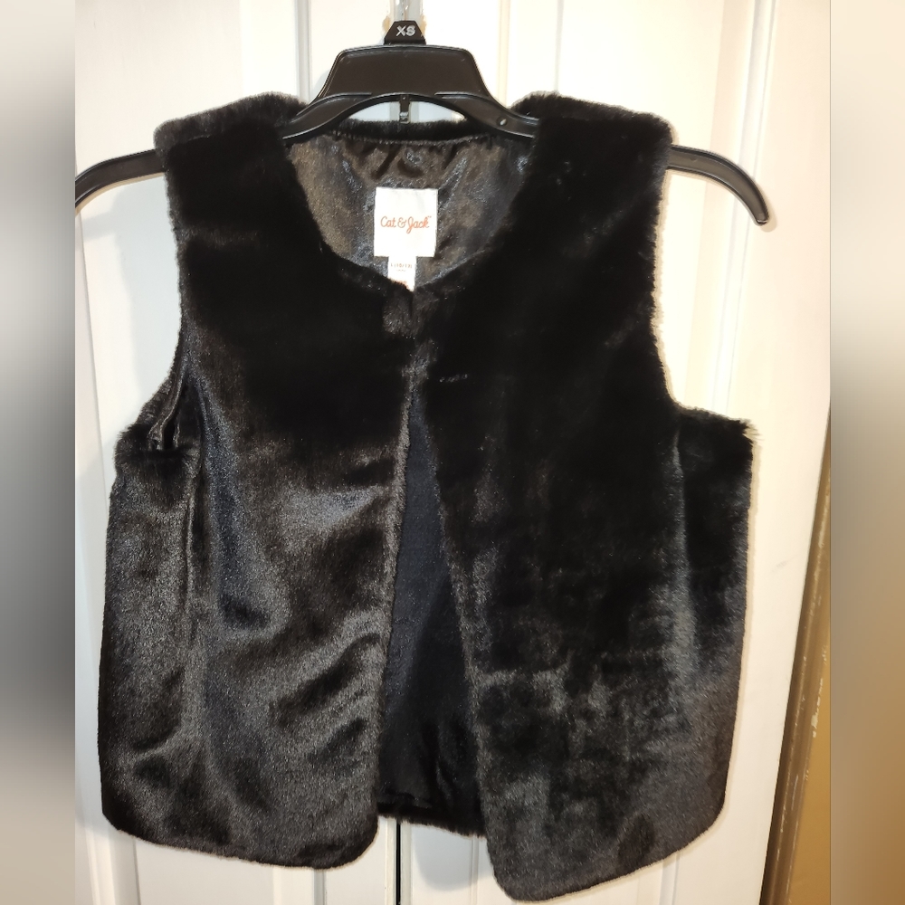 Black fuzzy vest with one fastening hook.